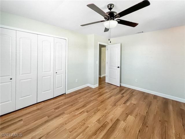 unfurnished bedroom featuring a closet, baseboards, light wood-style flooring, a ceiling fan, and visible vents