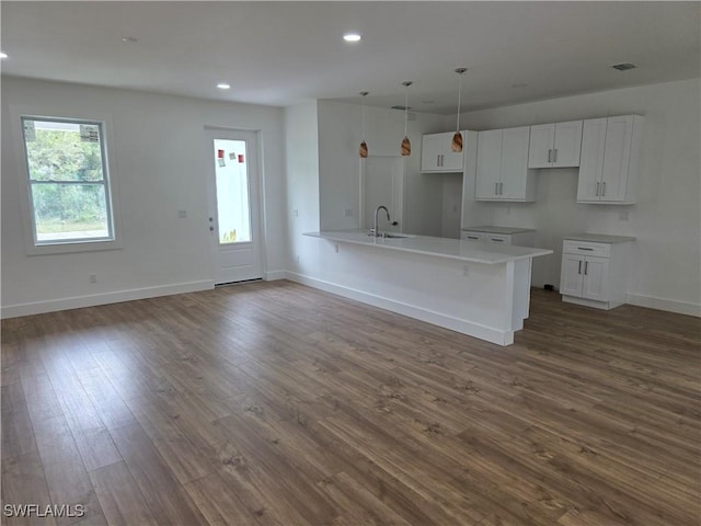 kitchen with dark wood-style floors, white cabinetry, baseboards, and a peninsula