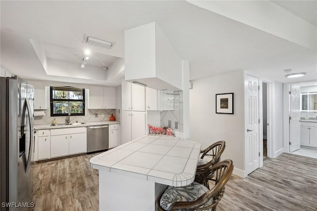 4967 Pepper Cir Unit 206, Naples, FL 34113 - kitchen featuring appliances with stainless steel finishes, light wood-style flooring, a peninsula, and tile counters