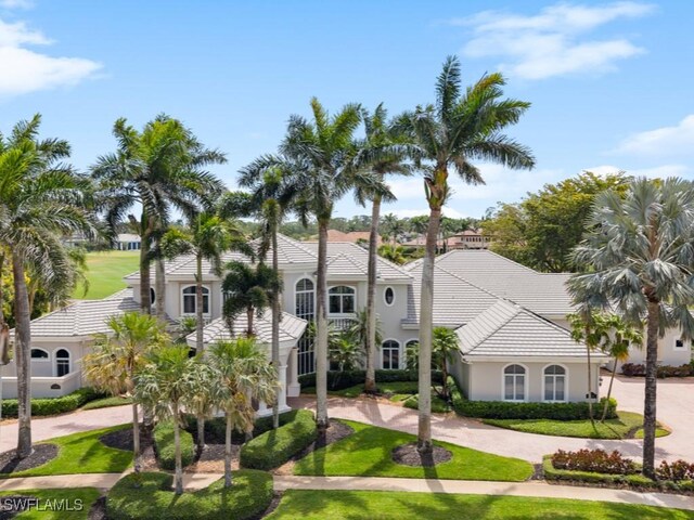 4244 Brynwood Dr, Naples, FL 34119 - mediterranean / spanish house featuring a front yard, stucco siding, a tiled roof, and curved driveway