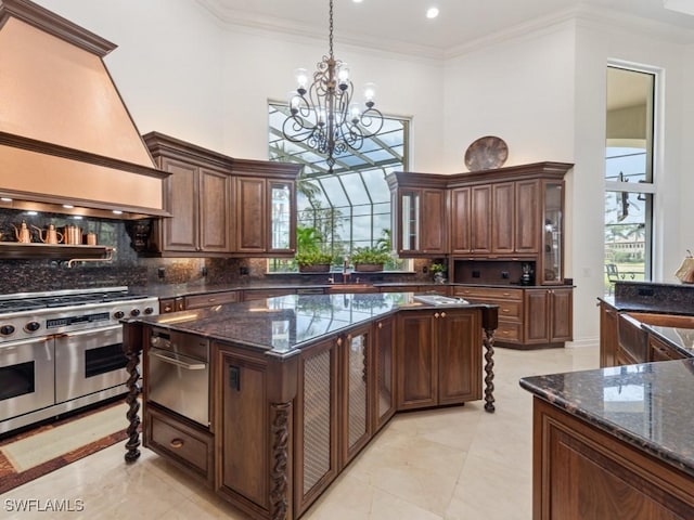 4244 Brynwood Dr, Naples, FL 34119 - kitchen featuring crown molding, premium range hood, an inviting chandelier, a high ceiling, and range with two ovens