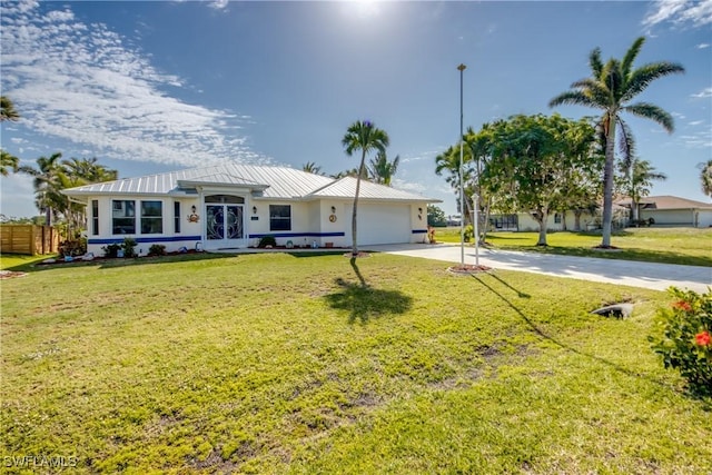 view of front of property with concrete driveway, a standing seam roof, metal roof, a front lawn, and a garage