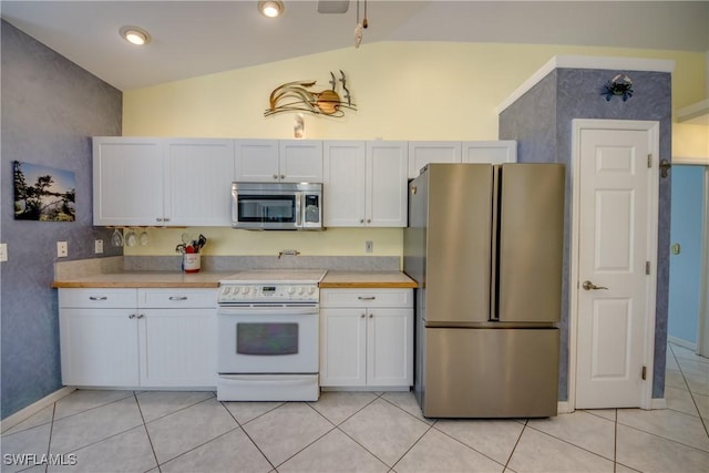 kitchen featuring light countertops, appliances with stainless steel finishes, white cabinetry, vaulted ceiling, and light tile patterned floors