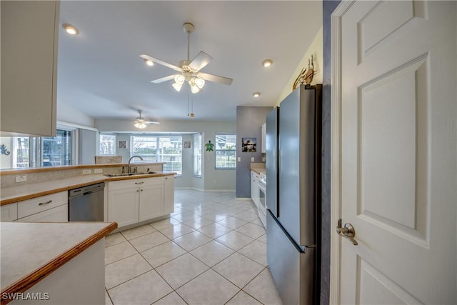 kitchen with light countertops, stainless steel appliances, white cabinetry, a sink, and light tile patterned floors