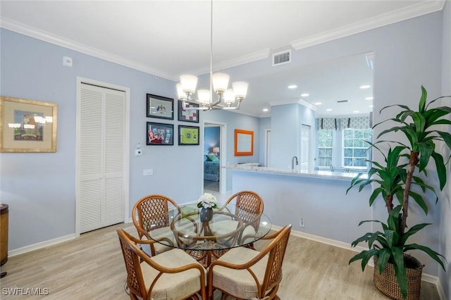dining room with visible vents, crown molding, light wood-style floors, and an inviting chandelier