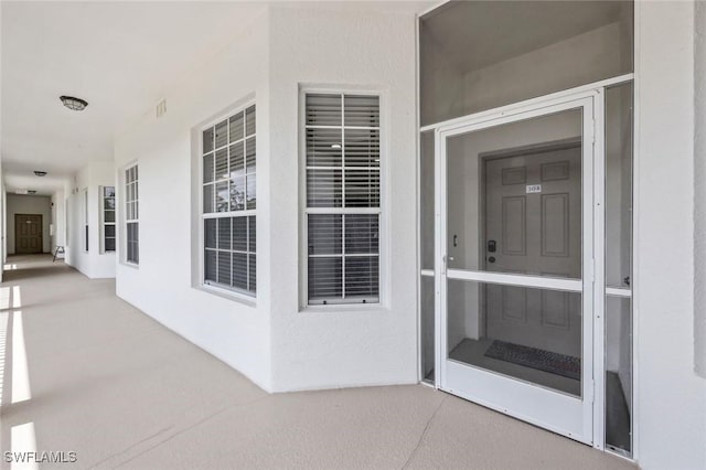 property entrance with stucco siding and visible vents