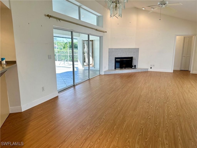 4830 Shearwater Ln, Naples, FL 34119 - unfurnished living room with high vaulted ceiling, light wood-style flooring, baseboards, ceiling fan, and a tiled fireplace