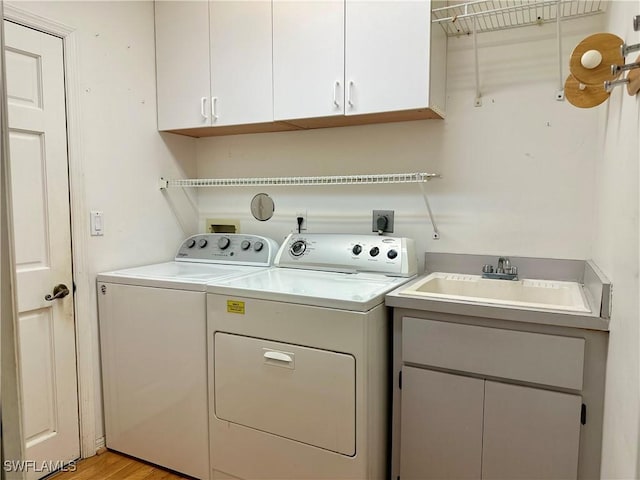 4830 Shearwater Ln, Naples, FL 34119 - laundry room with light wood finished floors, washer and clothes dryer, cabinet space, and a sink