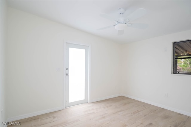 spare room featuring light wood finished floors, baseboards, and a ceiling fan