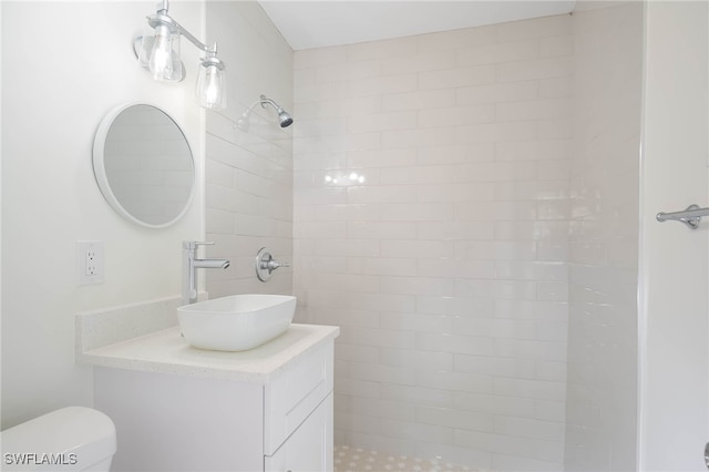 full bathroom featuring toilet, vanity, and a tile shower