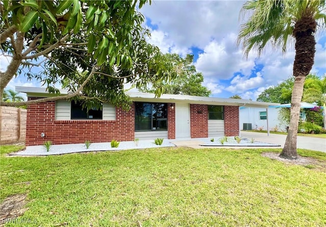 single story home with driveway, brick siding, and a front lawn