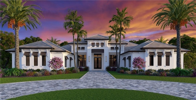 prairie-style house with french doors, stucco siding, and a front lawn