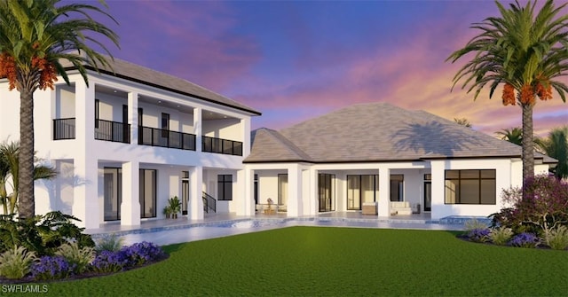 back of property at dusk featuring a shingled roof, a lawn, stucco siding, and a patio area