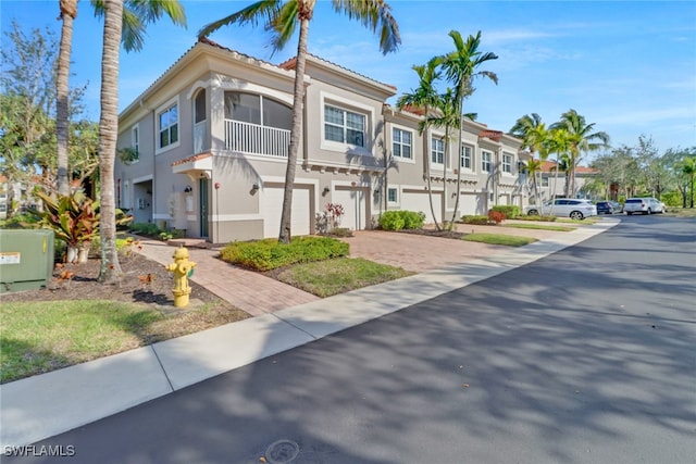 8521 Violeta St Unit 101, Estero, FL 34135 - view of front facade with a garage, a residential view, driveway, stucco siding, and a tile roof