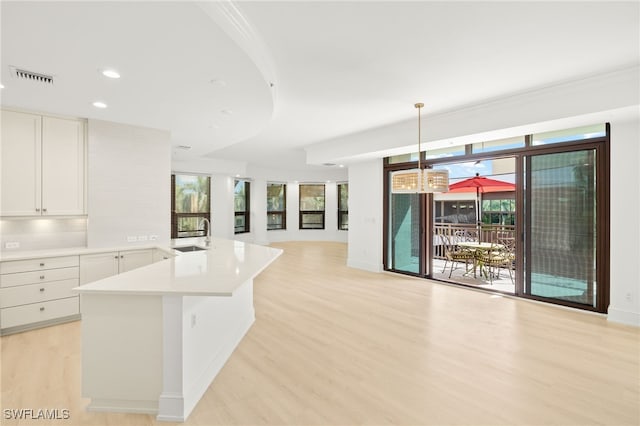 9123 Strada Pl Unit 7316, Naples, FL 34108 - kitchen with open floor plan, light wood-style flooring, light countertops, a sink, and white cabinets