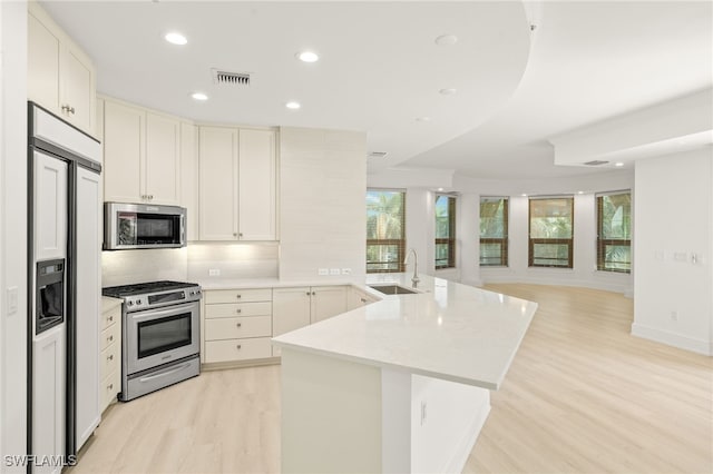 9123 Strada Pl Unit 7316, Naples, FL 34108 - kitchen featuring stainless steel appliances, a peninsula, a sink, light wood-type flooring, and recessed lighting