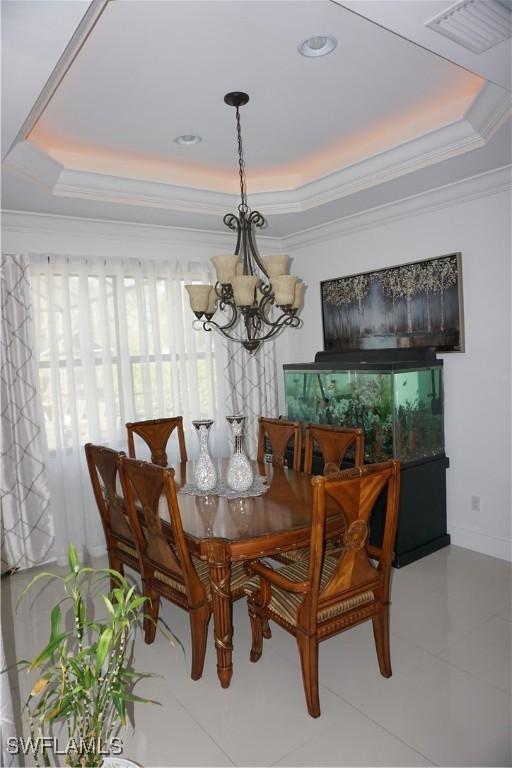 3393 21st Ave SW, Naples, FL 34117 - tiled dining area with visible vents, ornamental molding, a notable chandelier, and a tray ceiling