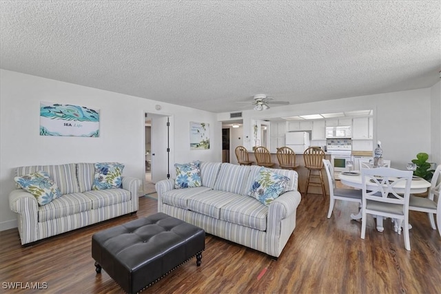 living area featuring visible vents, wood finished floors, ceiling fan, and a textured ceiling