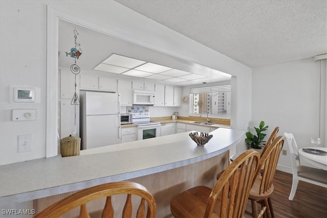 7148 Estero Blvd Unit 423, Fort Myers Beach, FL 33931 - kitchen with light countertops, a sink, a peninsula, dark wood-style floors, and white appliances