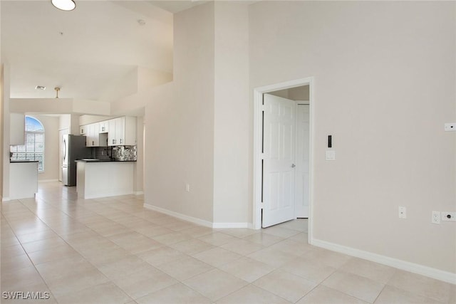 4940 Cougar Ct S Unit 201, Naples, FL 34109 - unfurnished room featuring light tile patterned floors, a towering ceiling, and baseboards