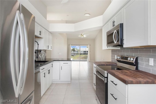 4940 Cougar Ct S Unit 201, Naples, FL 34109 - kitchen with stainless steel appliances, decorative backsplash, light tile patterned flooring, a ceiling fan, and a peninsula