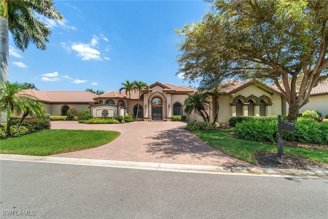 12581 Vittoria Way, Fort Myers, FL 33912 - mediterranean / spanish-style house featuring curved driveway, stucco siding, and a front lawn