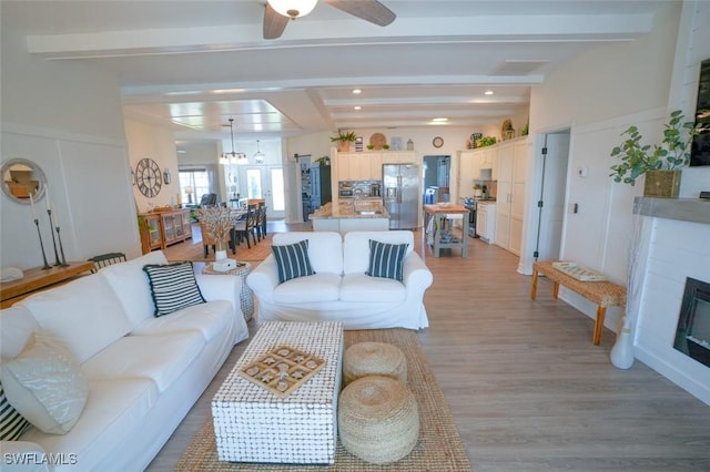 2533 SW 17th Pl, Cape Coral, FL 33914 - living room with ceiling fan with notable chandelier, beamed ceiling, light wood finished floors, visible vents, and a glass covered fireplace