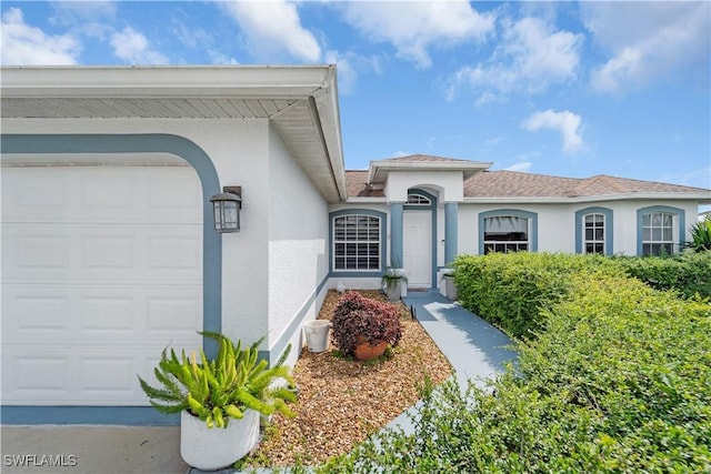 view of exterior entry featuring a garage and stucco siding
