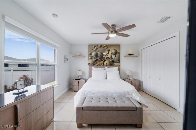 bedroom with a closet, a ceiling fan, visible vents, and light tile patterned floors