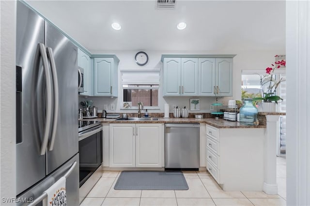 kitchen featuring visible vents, a peninsula, appliances with stainless steel finishes, a sink, and light tile patterned floors