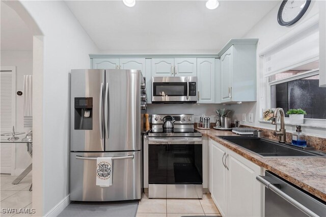 kitchen with arched walkways, a sink, stainless steel appliances, and light tile patterned floors