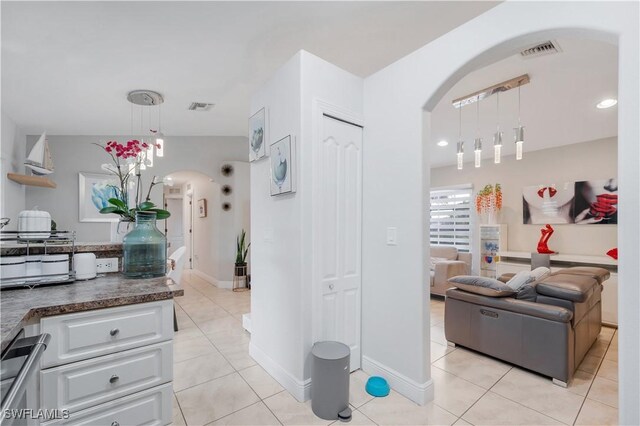 kitchen with hanging light fixtures, dark countertops, visible vents, white cabinets, and arched walkways