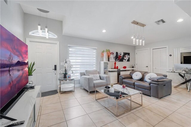 living room featuring light tile patterned flooring, a notable chandelier, visible vents, and recessed lighting
