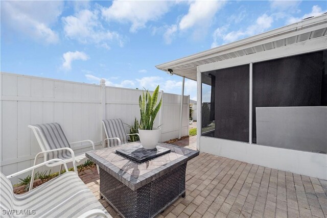 view of patio with a sunroom and fence