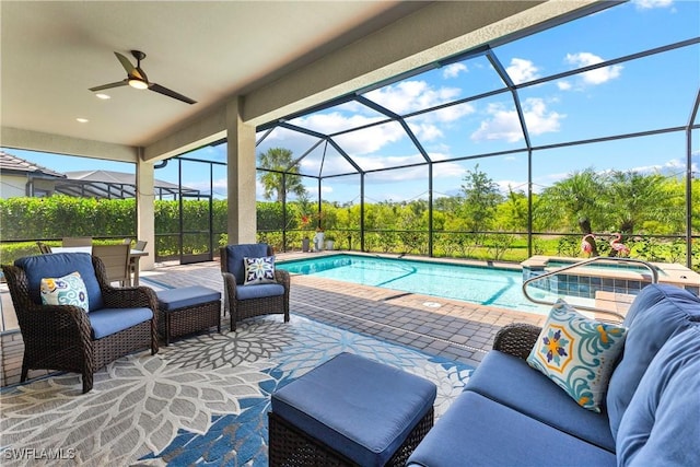 view of pool featuring a patio area, outdoor lounge area, ceiling fan, a pool with connected hot tub, and glass enclosure