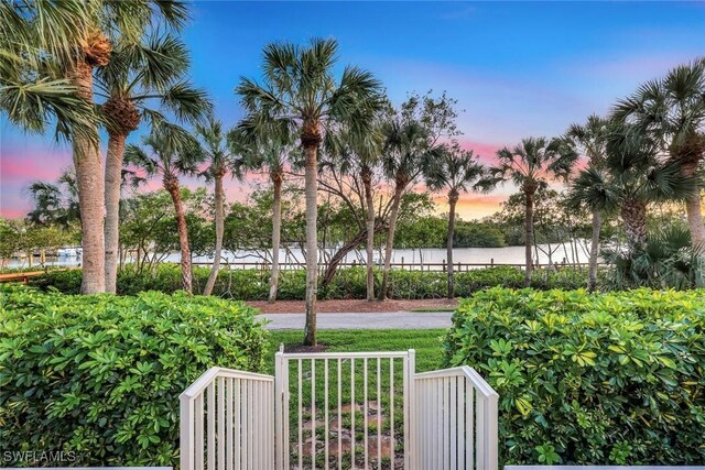 27571 Riverbank Dr, Bonita Springs, FL 34134 - yard at dusk featuring a water view and fence