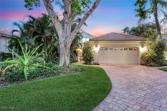 27571 Riverbank Dr, Bonita Springs, FL 34134 - mediterranean / spanish-style house with a tiled roof, stucco siding, a lawn, decorative driveway, and an attached garage