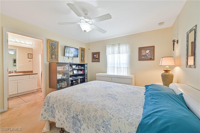 bedroom featuring ensuite bath, ceiling fan, a sink, and light colored carpet