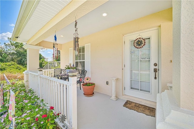view of exterior entry featuring a porch and stucco siding