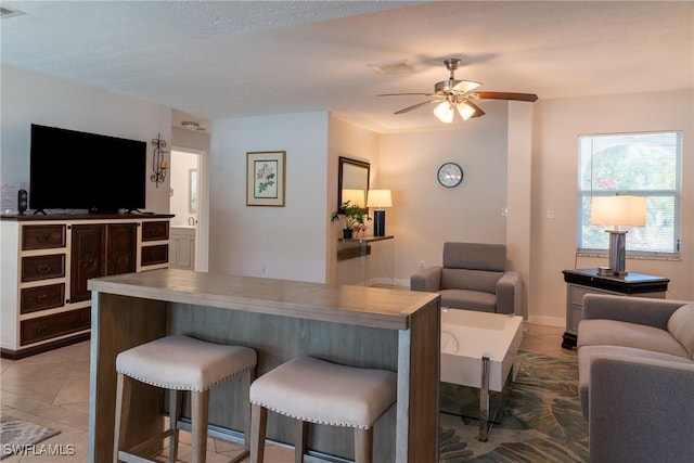 living area with baseboards, ceiling fan, visible vents, and light tile patterned floors