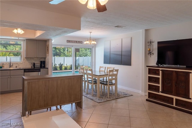 kitchen with a sink, dishwasher, gray cabinetry, visible vents, and decorative backsplash