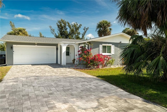 ranch-style house featuring a front lawn, decorative driveway, stucco siding, and an attached garage