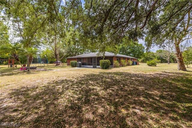 310 Trader Rd, Fort Denaud, FL 33935 - view of yard featuring a sunroom, a trampoline, and a playground