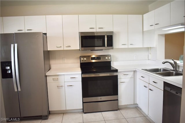 kitchen with light countertops, white cabinetry, light tile patterned flooring, stainless steel appliances, and a sink