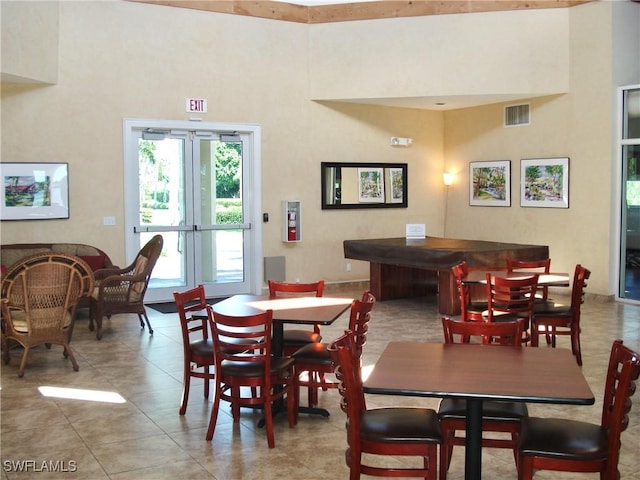 dining area featuring visible vents, a high ceiling, and light tile patterned floors