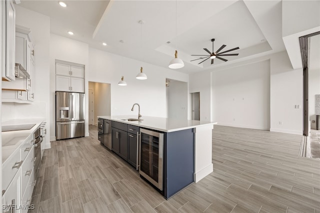 kitchen featuring wood tiled floor, beverage cooler, light countertops, a sink, and appliances with stainless steel finishes