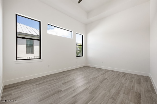 spare room with baseboards, a ceiling fan, and light wood-style floors