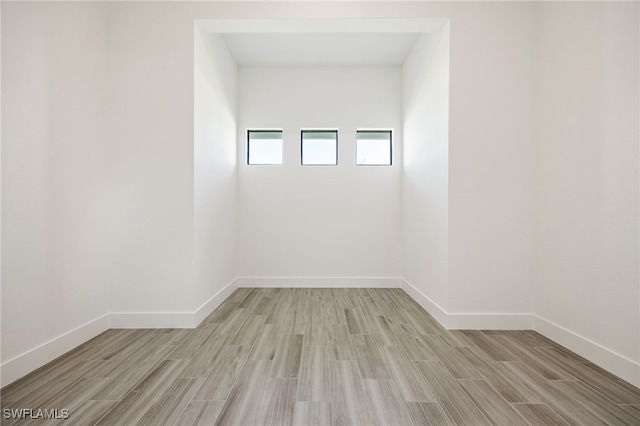 spare room with baseboards and light wood-type flooring