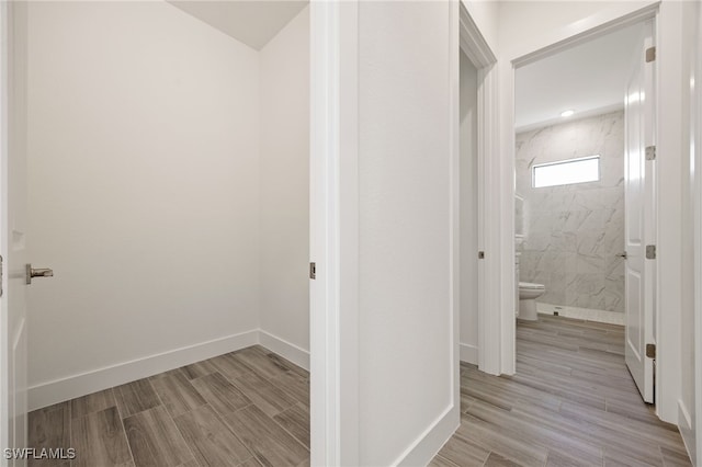 hallway featuring light wood-type flooring and baseboards