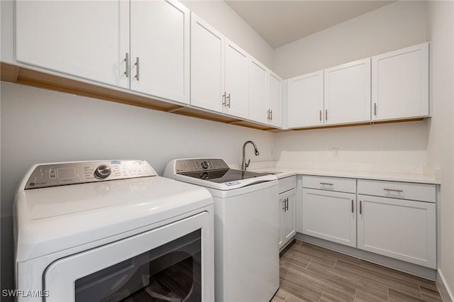 laundry area featuring light wood-type flooring, a sink, washer and dryer, and cabinet space